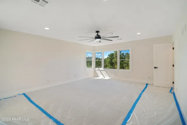 an empty room with windows and fan