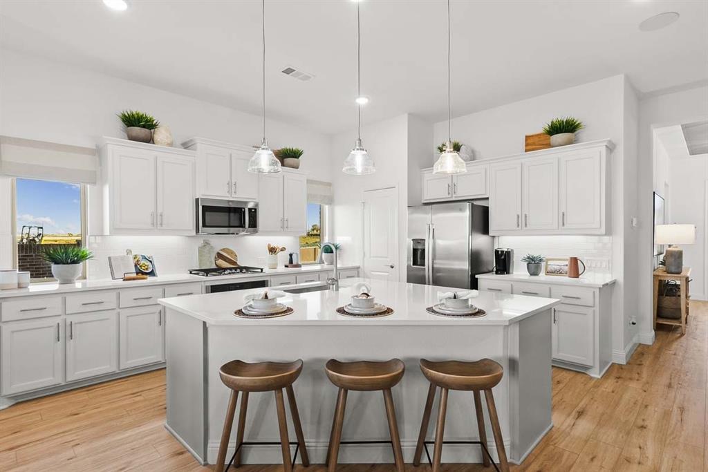 1439 Canadian Lane Van Alstyne, TX 75495 - Photo 5 of 21 a kitchen with stainless steel appliances kitchen island granite countertop a sink dishwasher and white cabinets with wooden floor