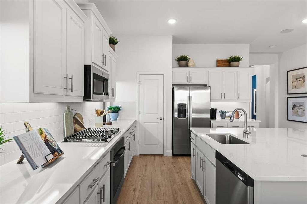 1439 Canadian Lane Van Alstyne, TX 75495 - Photo 6 of 21 a kitchen with stainless steel appliances granite countertop a stove top oven a sink a refrigerator white cabinets and wooden floor