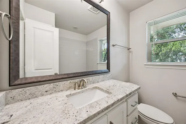a bathroom with a granite countertop sink toilet and mirror