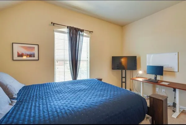 a bedroom with a bed and a lamp on dresser