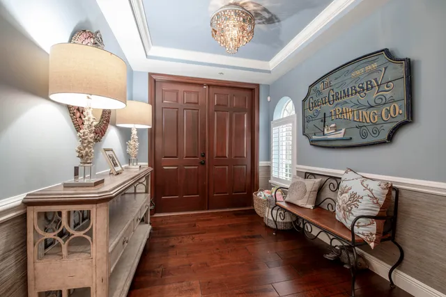 a dining room with wooden floor a chandelier a wooden table and chairs