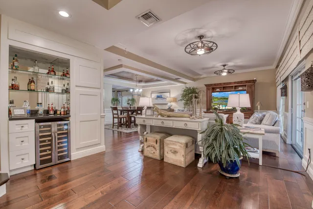 a view of a dining room and livingroom with furniture wooden floor a rug a fireplace and a chandelier