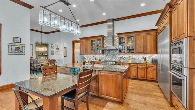 a kitchen with stainless steel appliances granite countertop a stove a refrigerator a oven a sink with a dining table and chairs