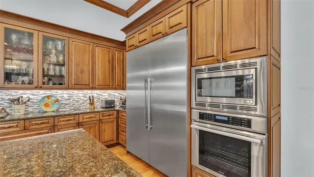 a kitchen with stainless steel appliances granite countertop a stove top oven a sink dishwasher and couches with wooden floor