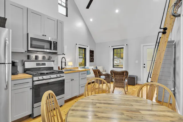 a kitchen with stainless steel appliances granite countertop a stove top oven a sink a dining table and chairs with wooden floor