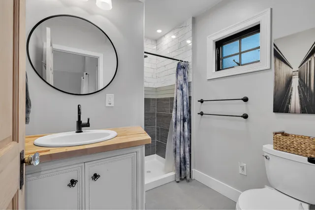 a bathroom with a sink a mirror a toilet and a shower