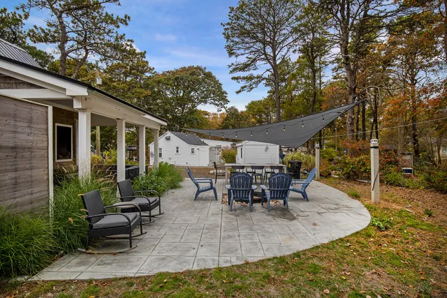 a view of a patio with table and chairs potted plants and large tree