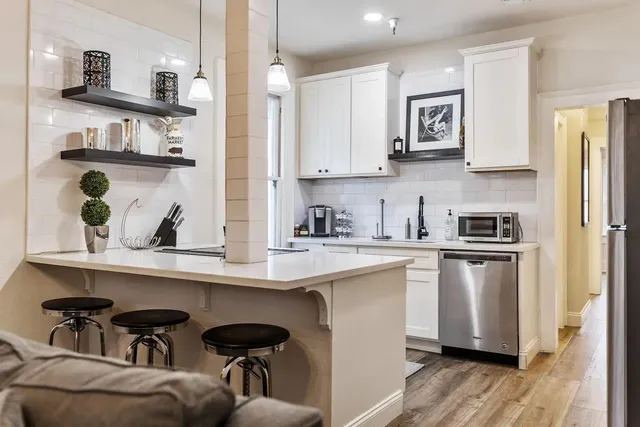 a kitchen with stainless steel appliances granite countertop a sink dishwasher stove and white cabinets with wooden floor