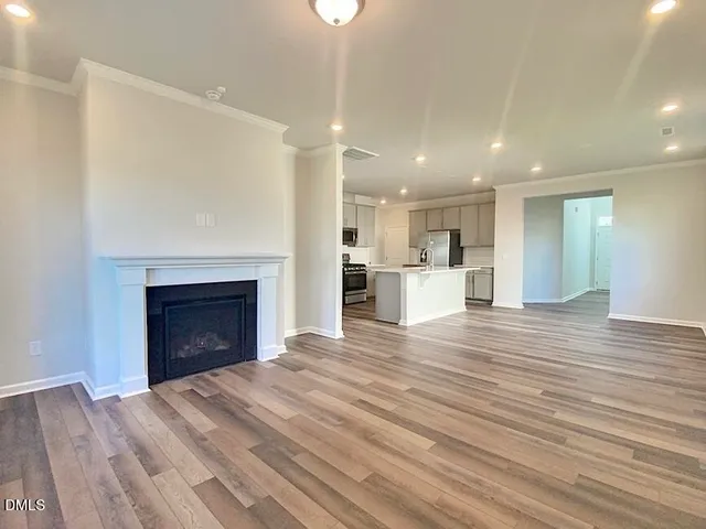 a view of kitchen and empty room with wooden floor