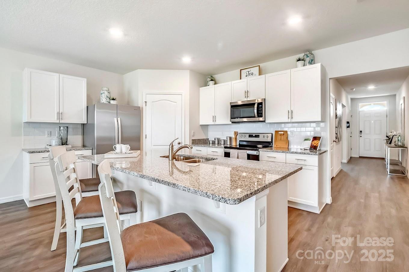 111 Switchgrass Loop, Unit ARIA Fairview, NC 28730 - Photo 4 of 20 a kitchen with stainless steel appliances granite countertop a stove a sink a microwave a refrigerator and white cabinets with wooden floor
