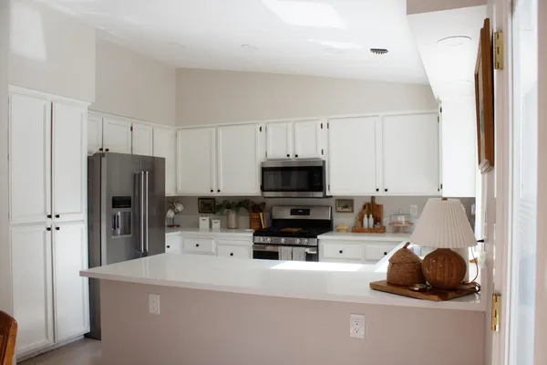 a kitchen with stainless steel appliances a refrigerator a sink a stove and white cabinets