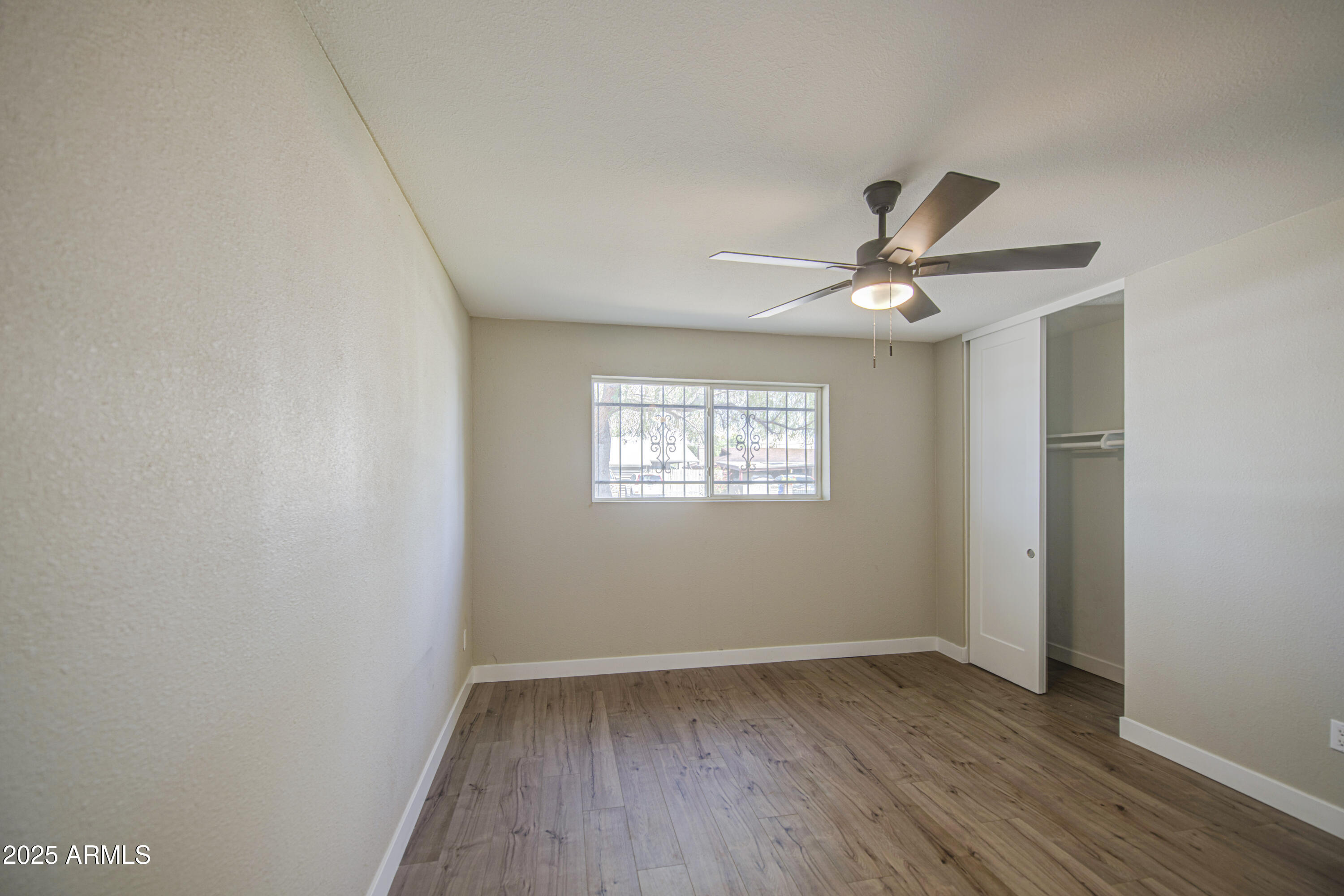 4750 North 39th Drive Phoenix, AZ 85019 - Photo 21 of 39 an empty room with wooden floor fan and windows