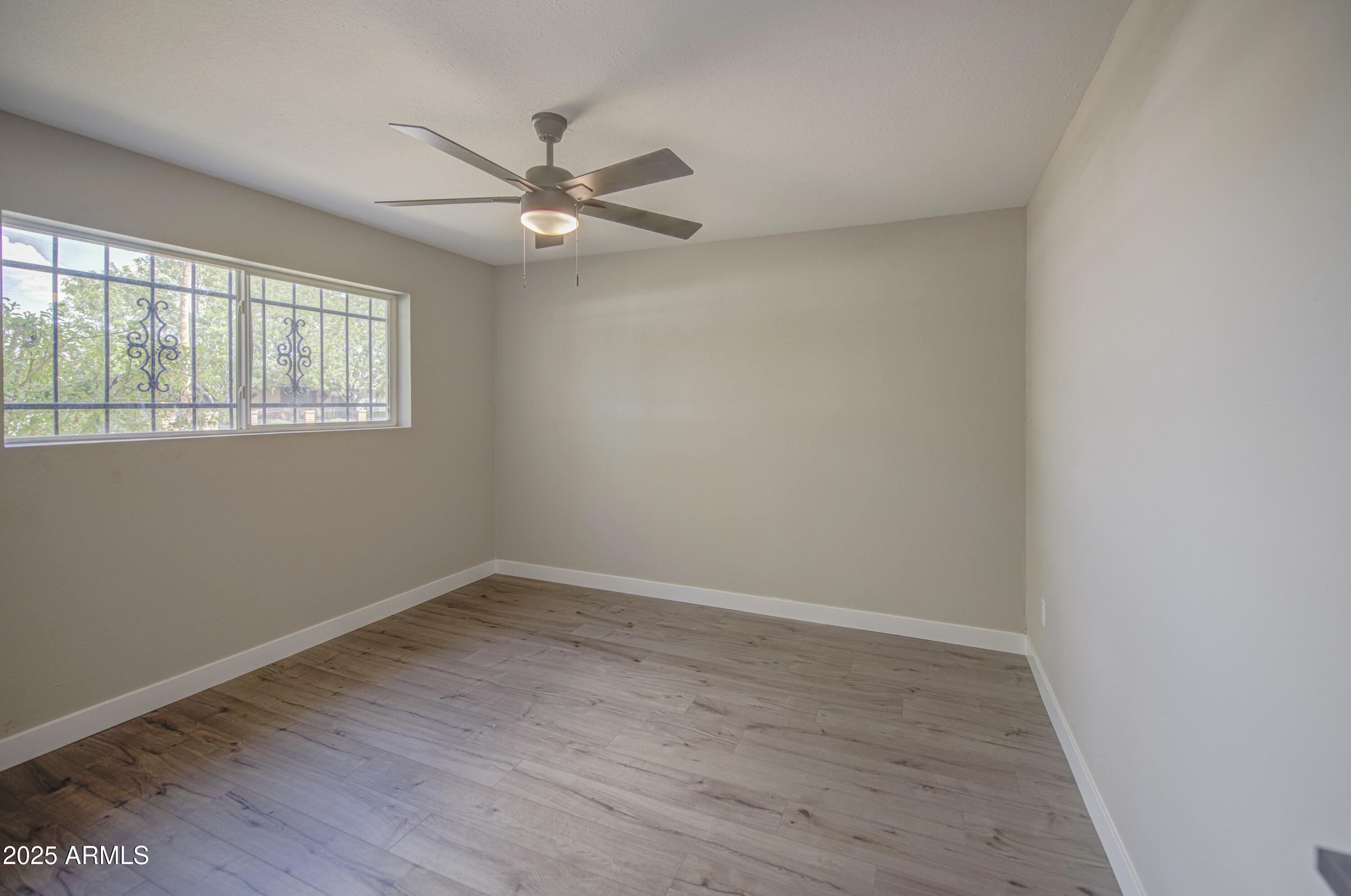 4750 North 39th Drive Phoenix, AZ 85019 - Photo 32 of 39 an empty room with wooden floor fan and windows