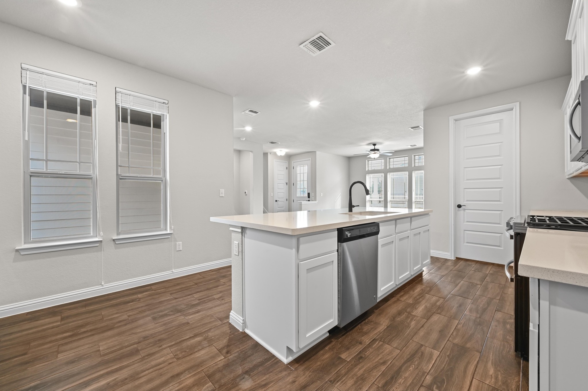 8003 Orizzonte Street Austin, TX 78744 - Photo 13 of 25 Kitchen with dark wood finished floors, an island with sink, recessed lighting, white cabinetry, and stainless steel appliances
