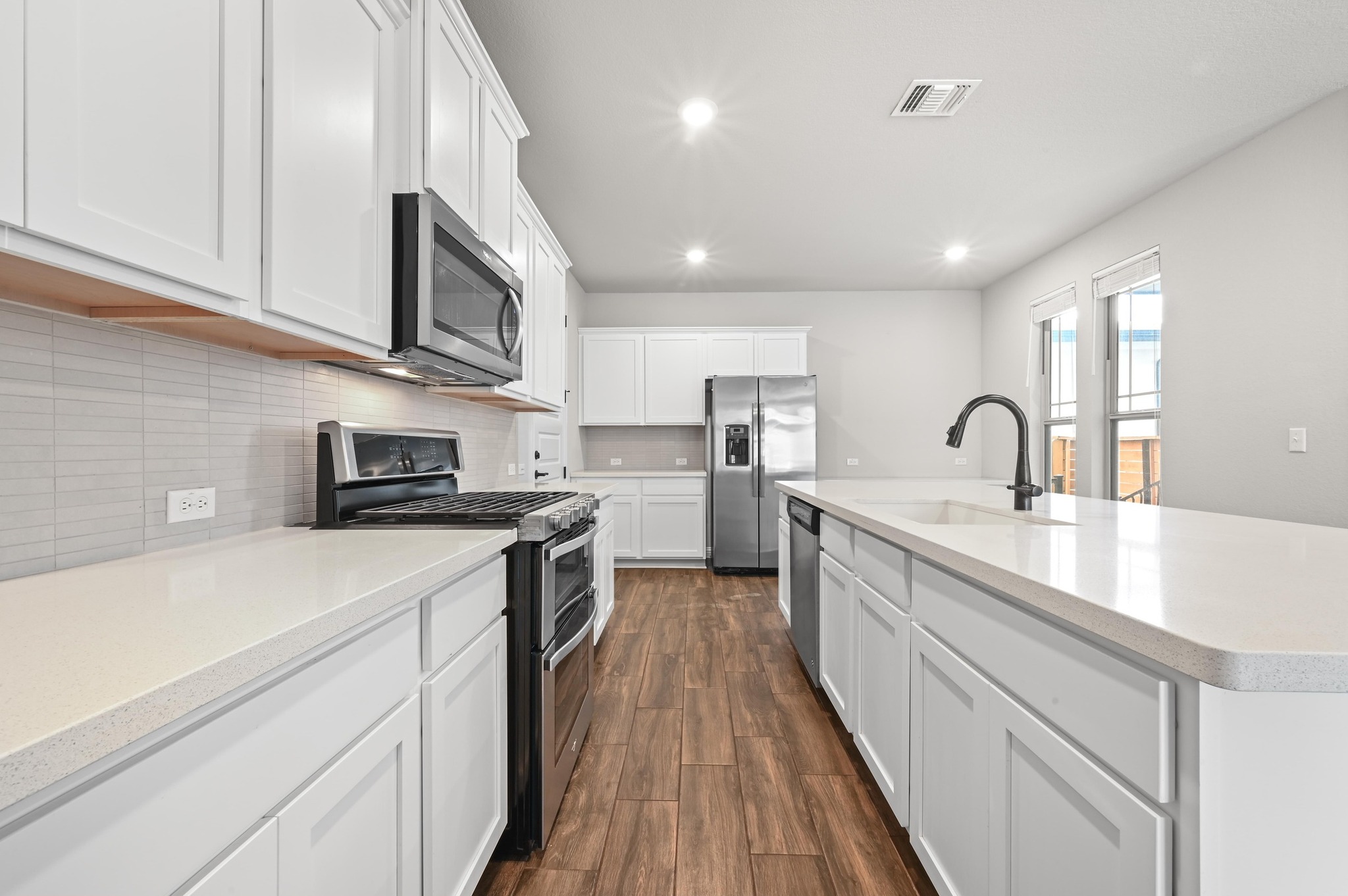 8003 Orizzonte Street Austin, TX 78744 - Photo 14 of 25 Kitchen featuring stainless steel appliances, white cabinets, dark wood-type flooring, a center island with sink, and recessed lighting