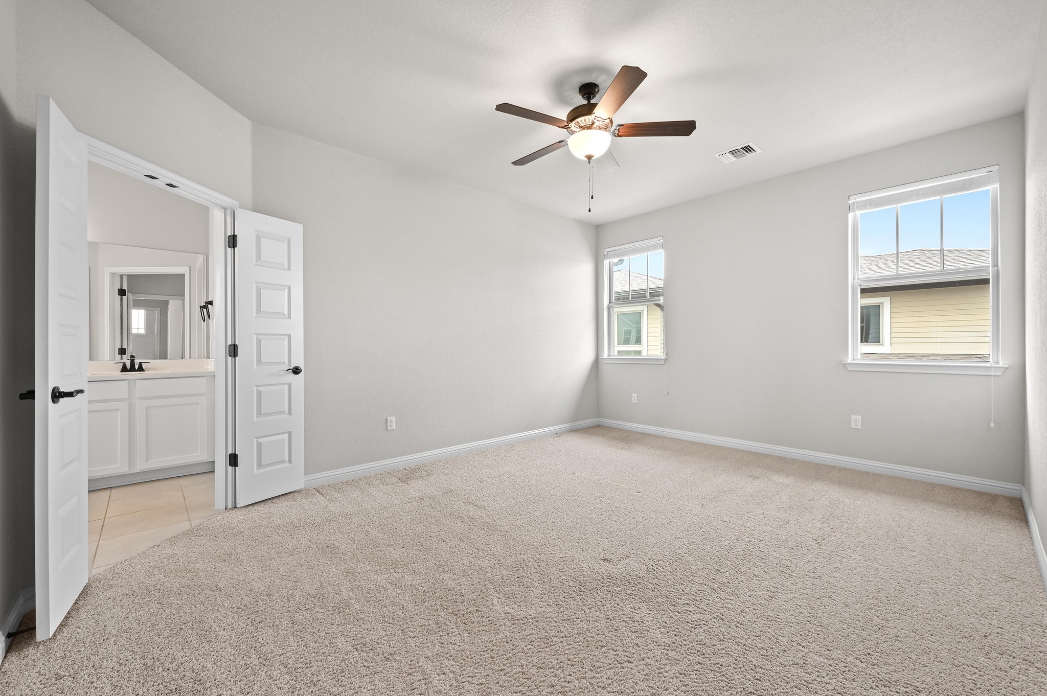 8003 Orizzonte Street Austin, TX 78744 - Photo 17 of 25 Unfurnished bedroom with light carpet, ceiling fan, and connected bathroom