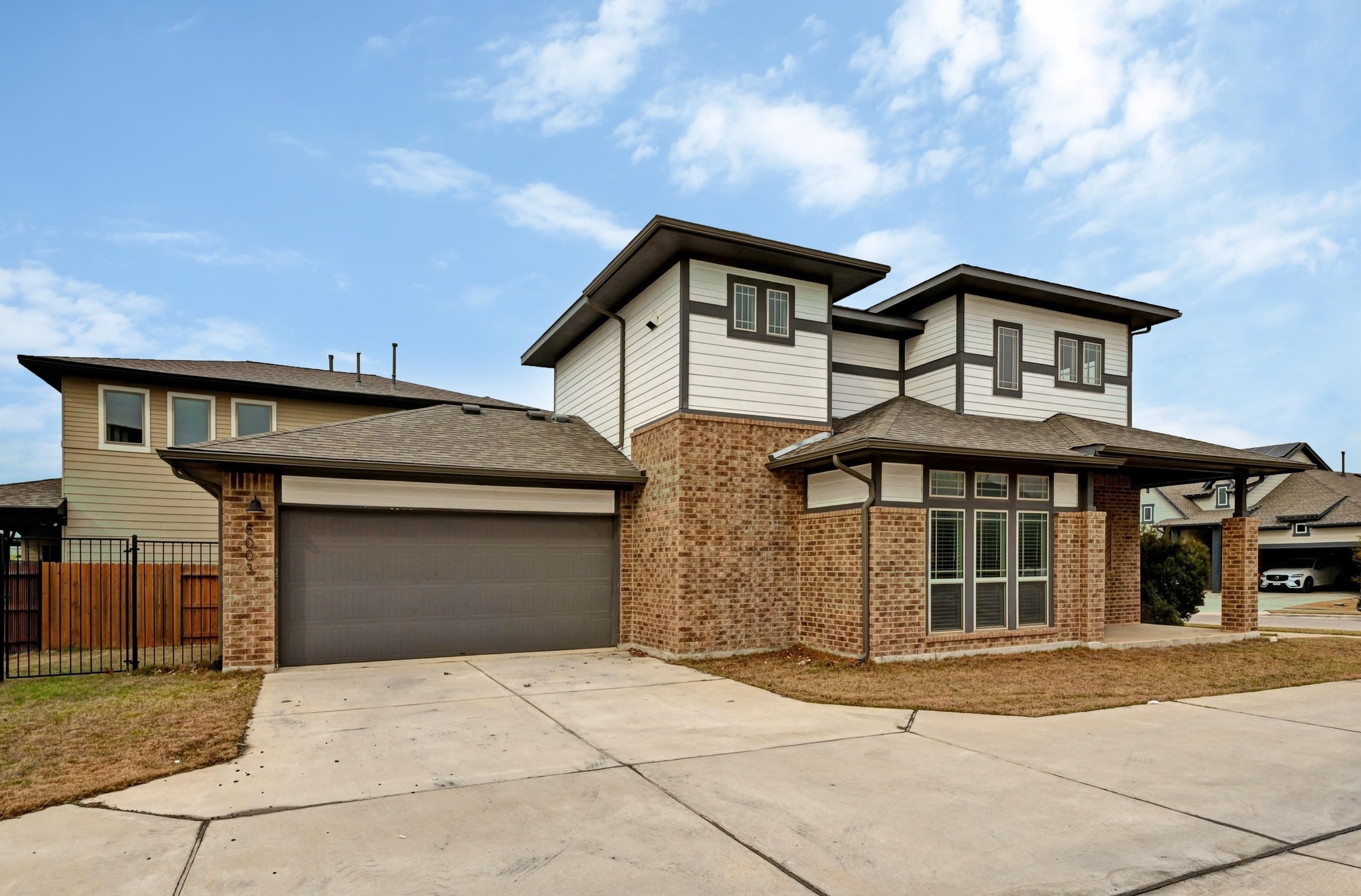 8003 Orizzonte Street Austin, TX 78744 - Photo 3 of 25 Prairie-style house with driveway, brick siding, roof with shingles, and a garage