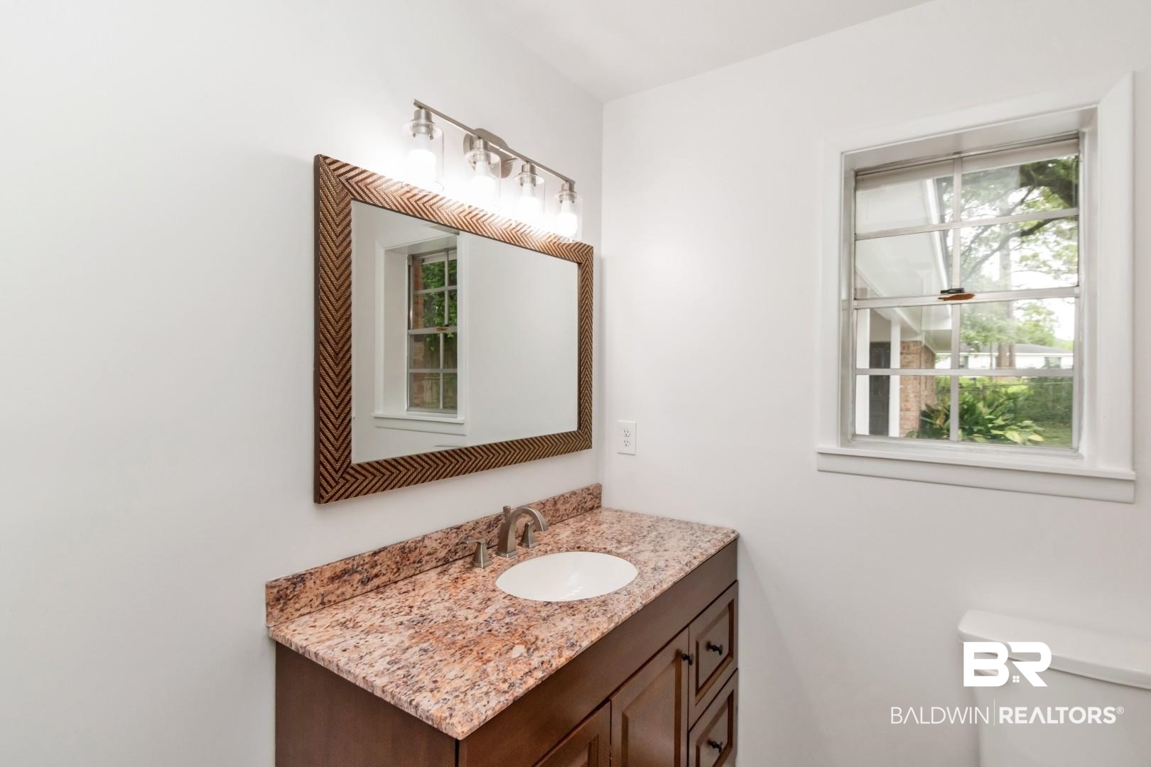 5217 Perin Road Mobile, AL 36693 - Photo 12 of 45 Bathroom vanity featuring a vessel sink, brown cabinetry, and a patterned mirror