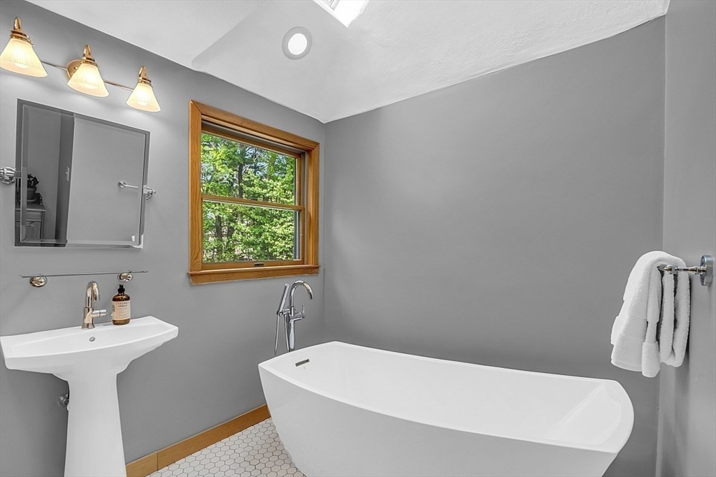 3 Valley Road North Reading, MA 01864 - Photo 19 of 42 a bathroom with a white bath tub a sink and a window