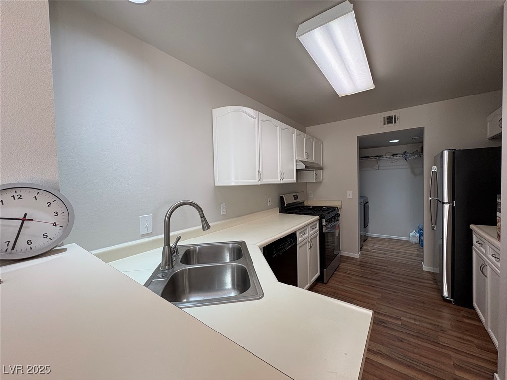 7931 Trea Avenue Las Vegas, NV 89147 - Photo 8 of 25 Kitchen featuring light countertops, stainless steel appliances, white cabinets, and dark wood-style floors