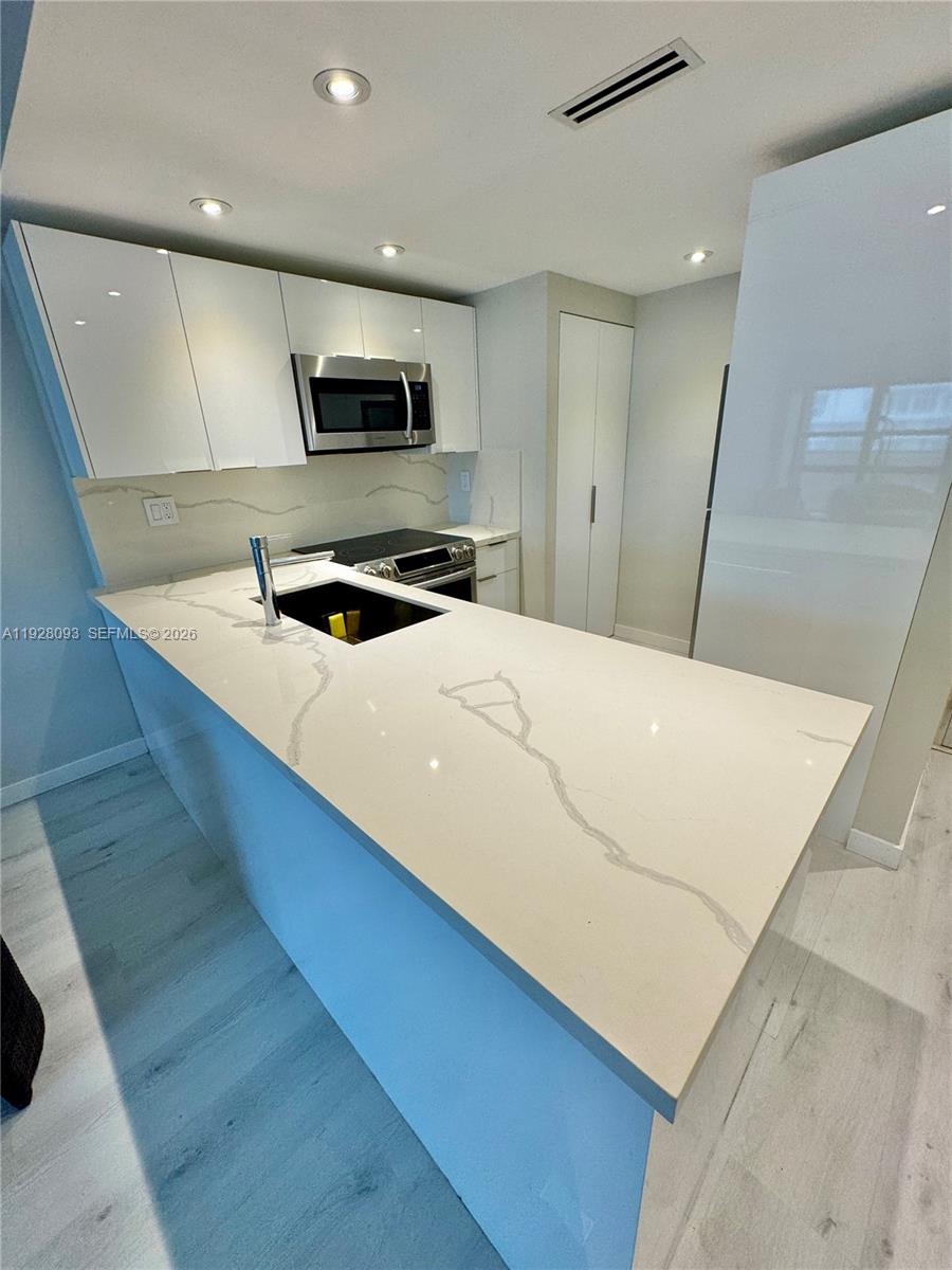 600 Northeast 36th Street, Unit 720 Miami, FL 33137 - Photo 2 of 26 a large white kitchen with stainless steel appliances a stove a microwave a sink and white cabinets