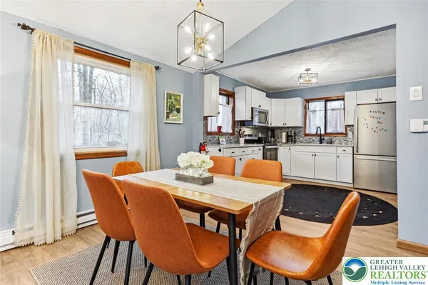 a kitchen with stainless steel appliances kitchen island granite countertop a dining table chairs and a refrigerator