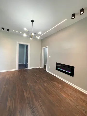 an empty room with wooden floor chandelier and windows