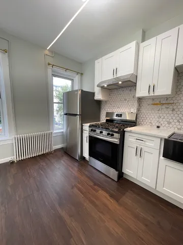 a kitchen with granite countertop a refrigerator and a stove top oven