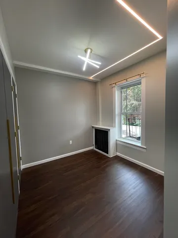 an empty room with wooden floor fireplace and windows