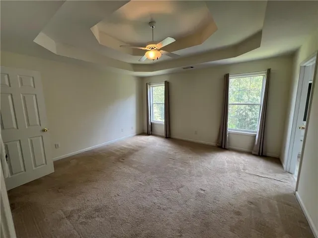an empty room with chandelier fan and windows