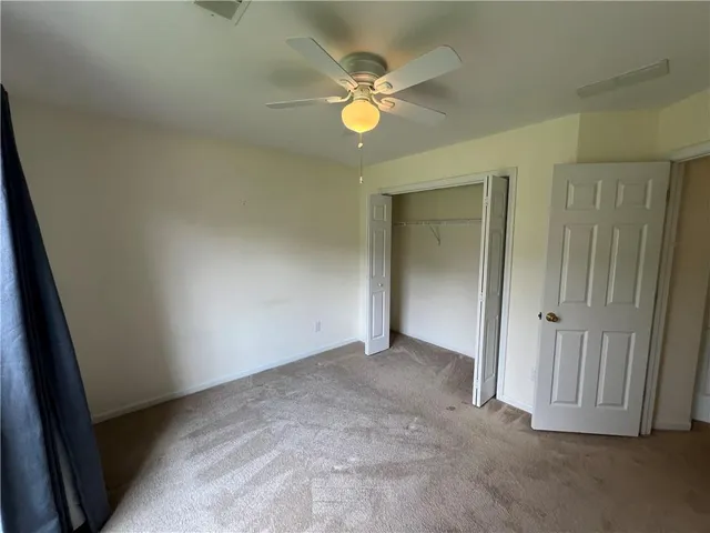 an empty room with closet and a chandelier fan