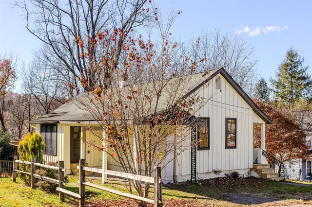 a view of a white house with a large tree