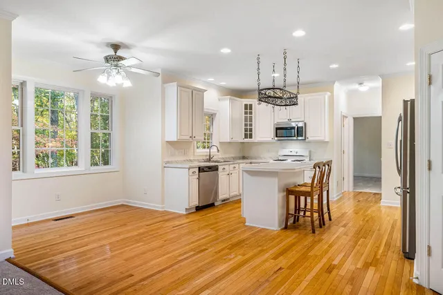 a kitchen with stainless steel appliances kitchen island granite countertop a sink cabinets and wooden floor