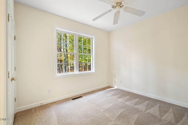an empty room with a window and a fan