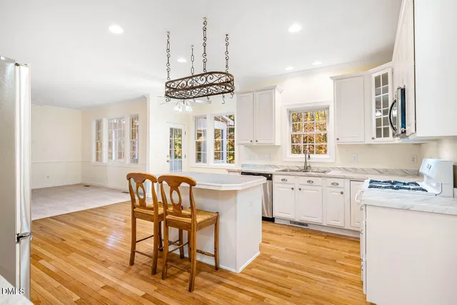 a kitchen with granite countertop a stove a sink a dining table and chairs