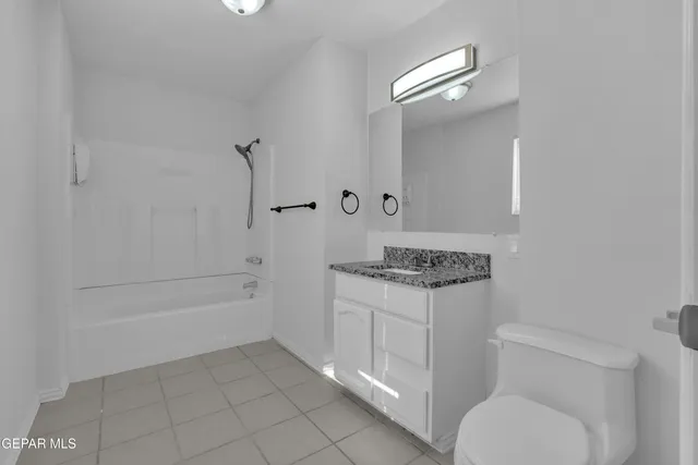 an empty room with ceiling fan and windows