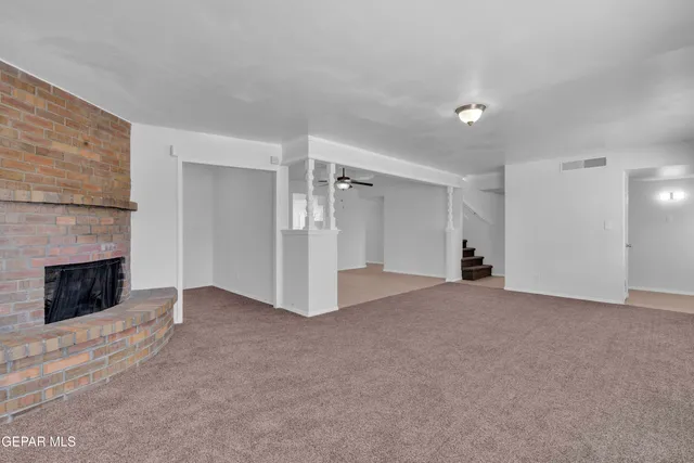 an empty room with chandelier fan and windows