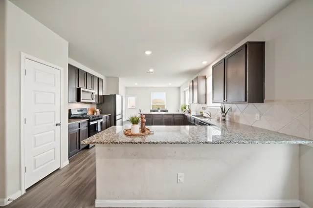 a large kitchen with granite countertop a large counter top stainless steel appliances and cabinets