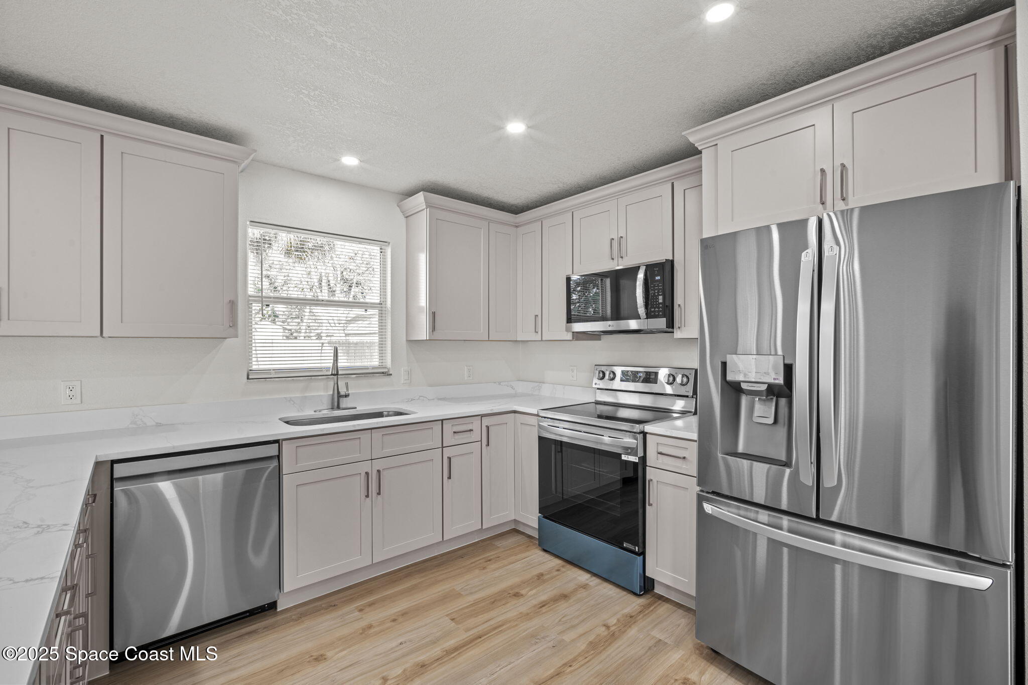 5130 Carter Street Cocoa, FL 32927 - Photo 13 of 33 a kitchen with granite countertop stainless steel appliances a sink cabinets and a window