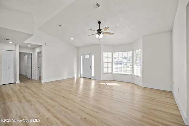 a view of an empty room with a window and wooden floor