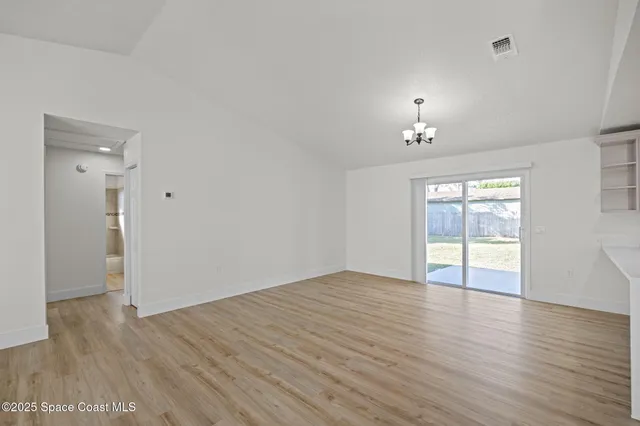 an empty room with wooden floor and window