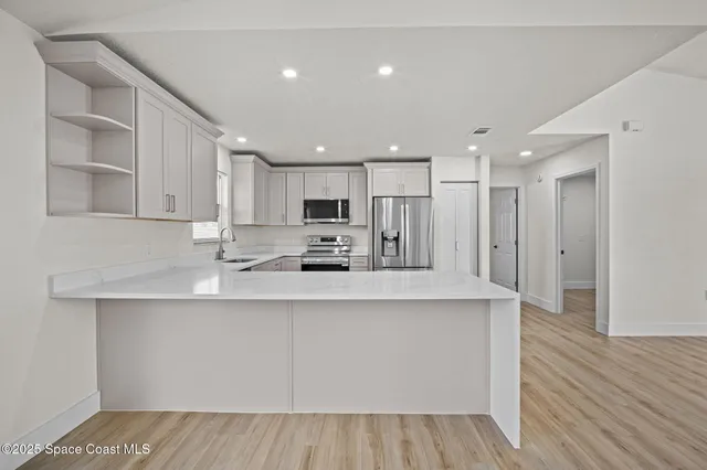 a large white kitchen with kitchen island a sink a center island stainless steel appliances and a cabinets