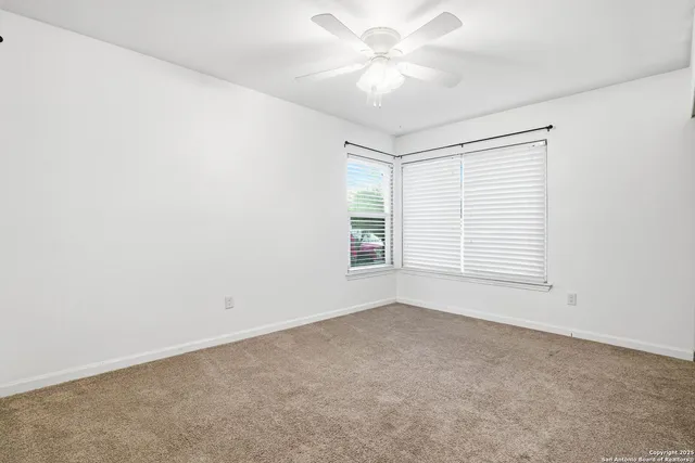 an empty room with a ceiling fan and window