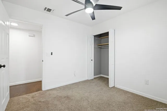 a view of an empty room with a ceiling fan