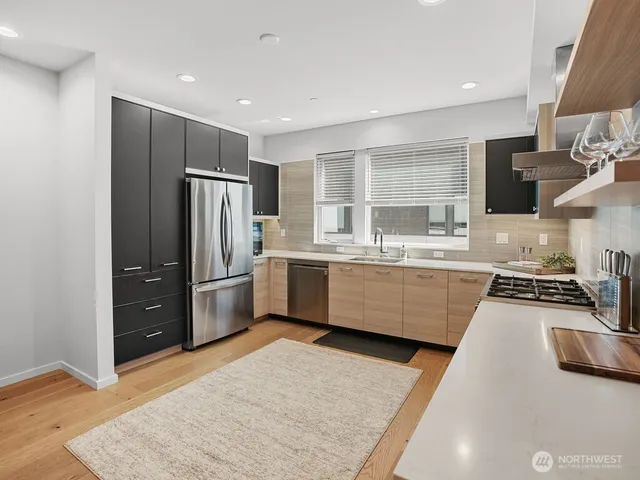 a kitchen with stainless steel appliances a sink a stove a refrigerator and cabinets