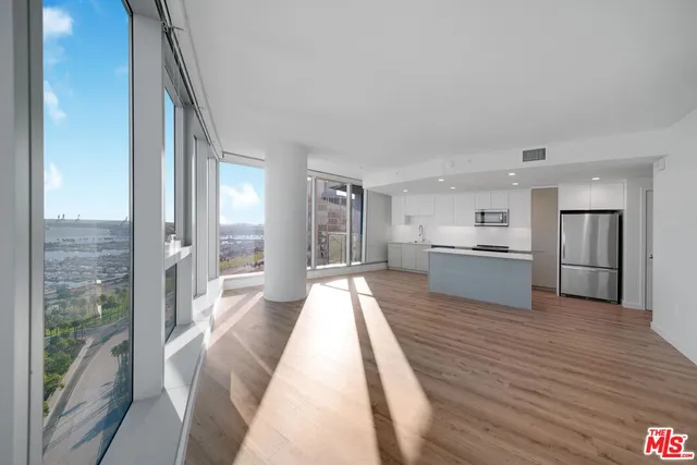 a view of a kitchen with kitchen island a stove wooden floor wooden floor and a large window