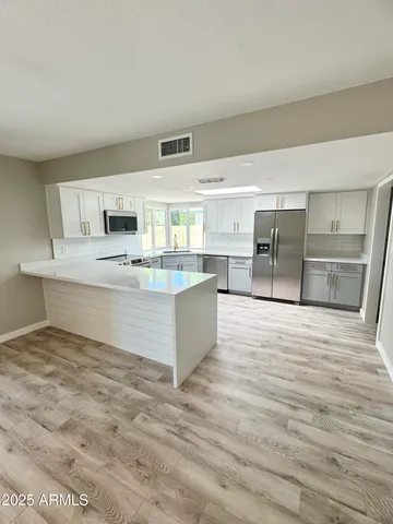 a large white kitchen with kitchen island a sink stainless steel appliances and cabinets