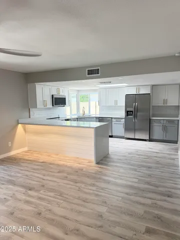 a large white kitchen with kitchen island a sink stainless steel appliances and cabinets