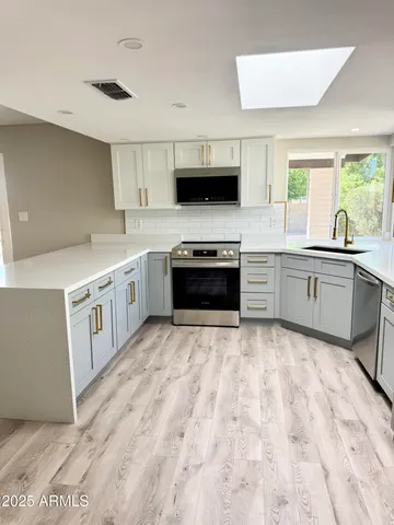 a large kitchen with stainless steel appliances granite countertop a stove and a sink